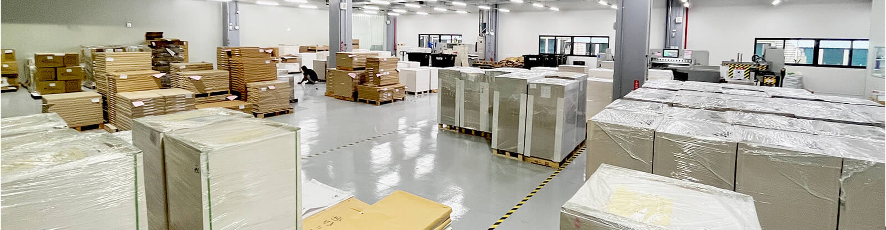 NTI production aisle — palletised stock between press and finishing