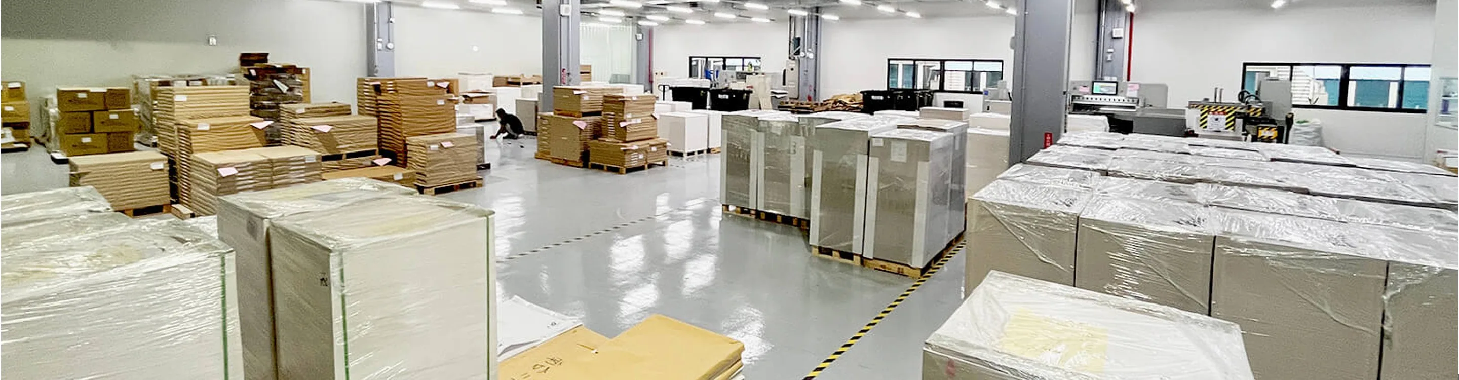 NTI production aisle — palletised stock between press and finishing